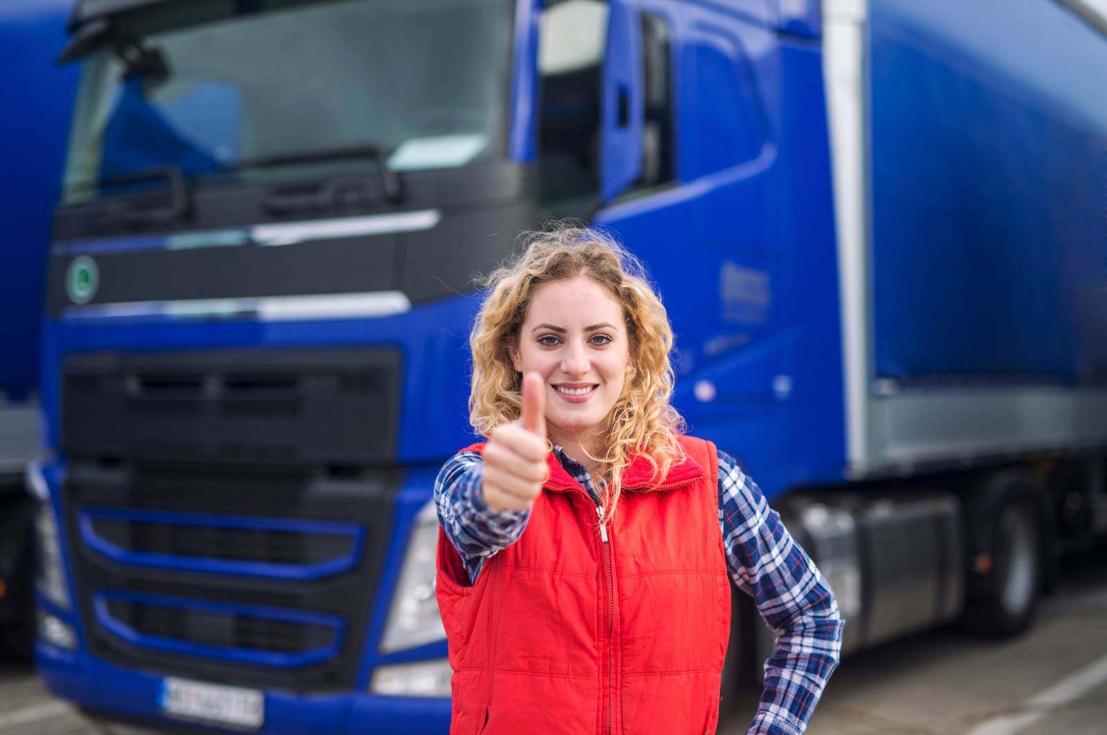 Retrato de motorista de caminhão profissional mostrando os polegares para cima e sorrindo.